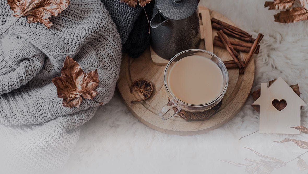 Fallen autumn leaves on a blanket with a cup of coffee and cinnamon sticks.