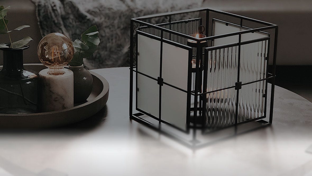 A Modern Impressions Votive Holder sitting on a marble coffee table.