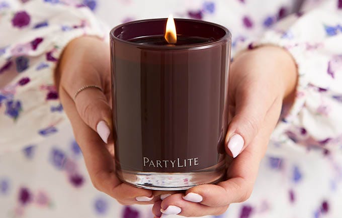 Woman holding a lit dark scented candle.